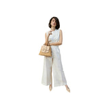 The Tiny Finch Lady Latte bag in handwoven rattan with embossed lizard leather details held by a model in white linen