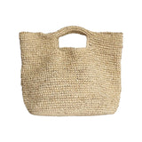 The Tiny Finch Marina bag in natural raffia with a square shape and cutout handles for a flexible organic look.