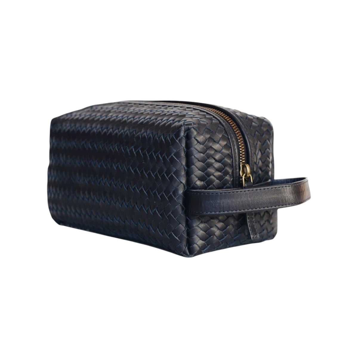 The Tiny Finch navy blue woven leather dopp kit with a side handle and brass zipper closure for travel toiletries.