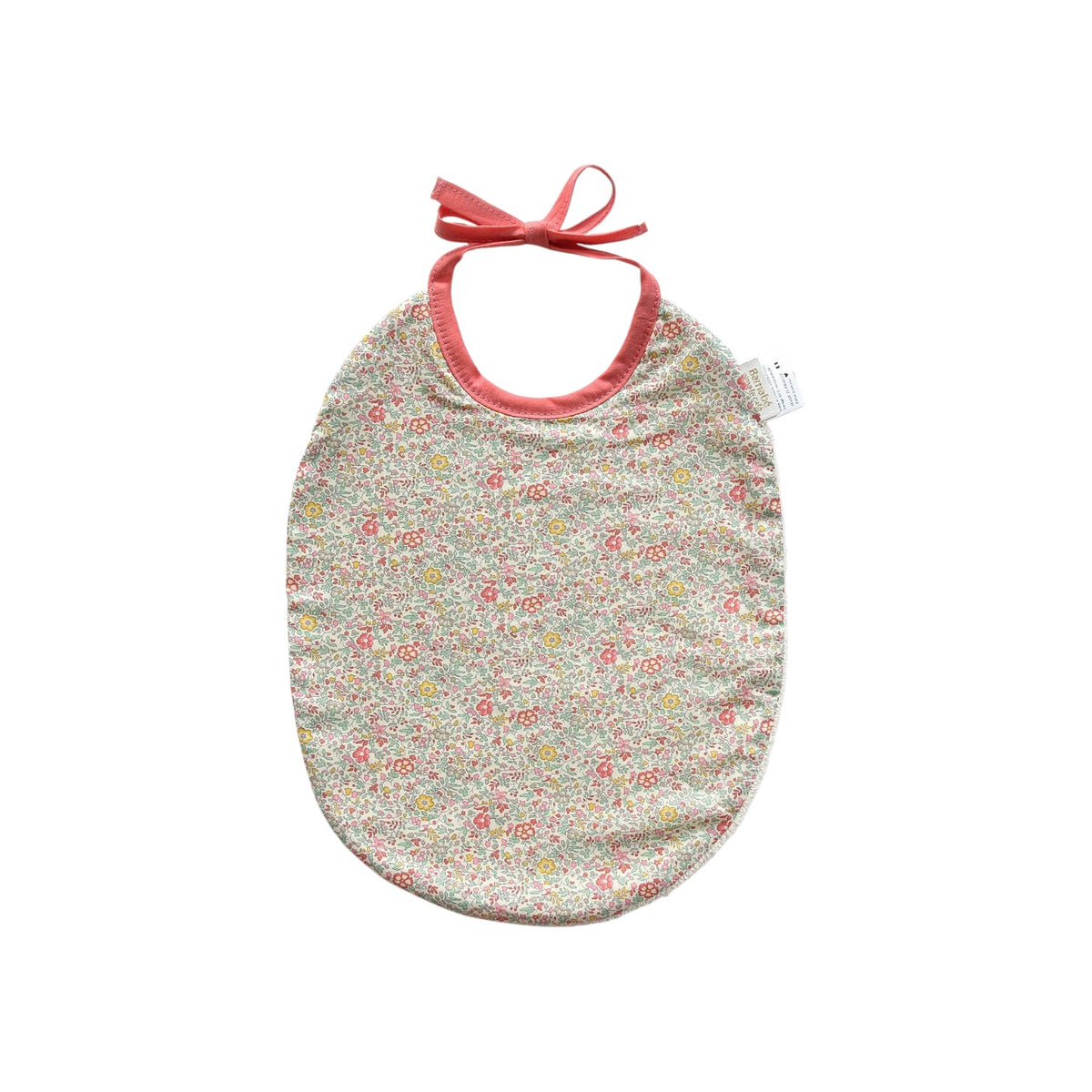 The Tiny Finch Paloma baby bib in floral Liberty fabric with pink trim and tie closure on a white background.