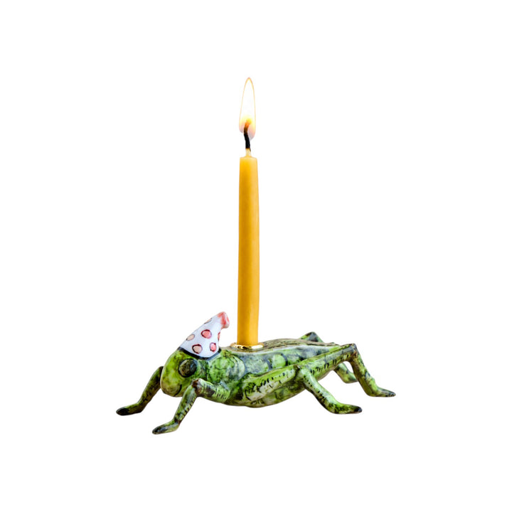The Tiny Finch porcelain cricket cake topper with a hand-painted green finish and a festive party hat holding a candle