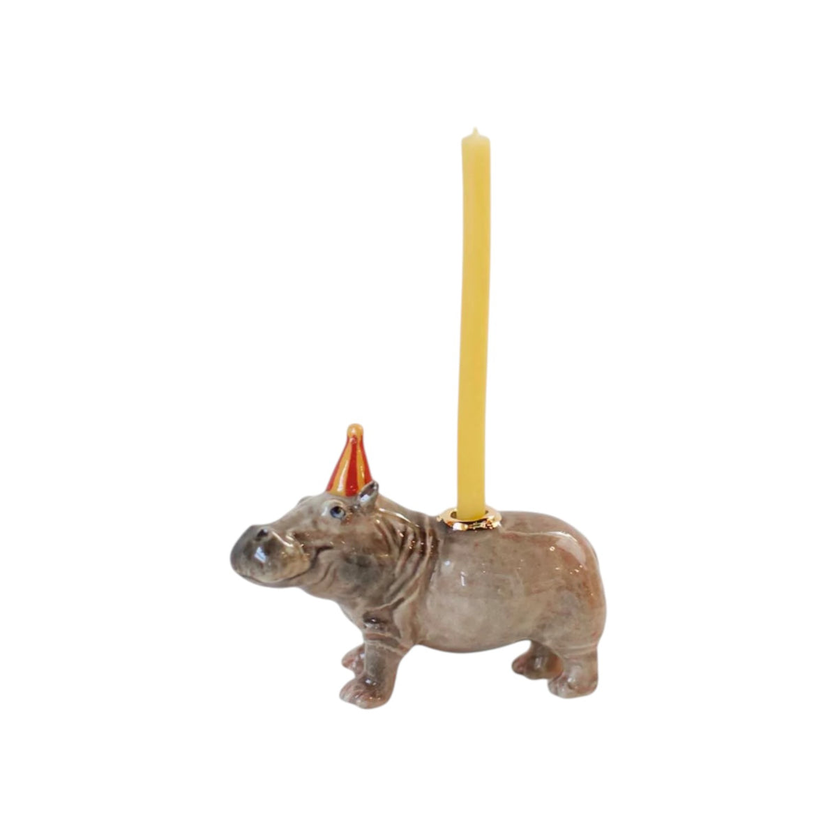 The Tiny Finch hand-painted porcelain hippo cake topper wearing a red party hat with a yellow birthday candle.