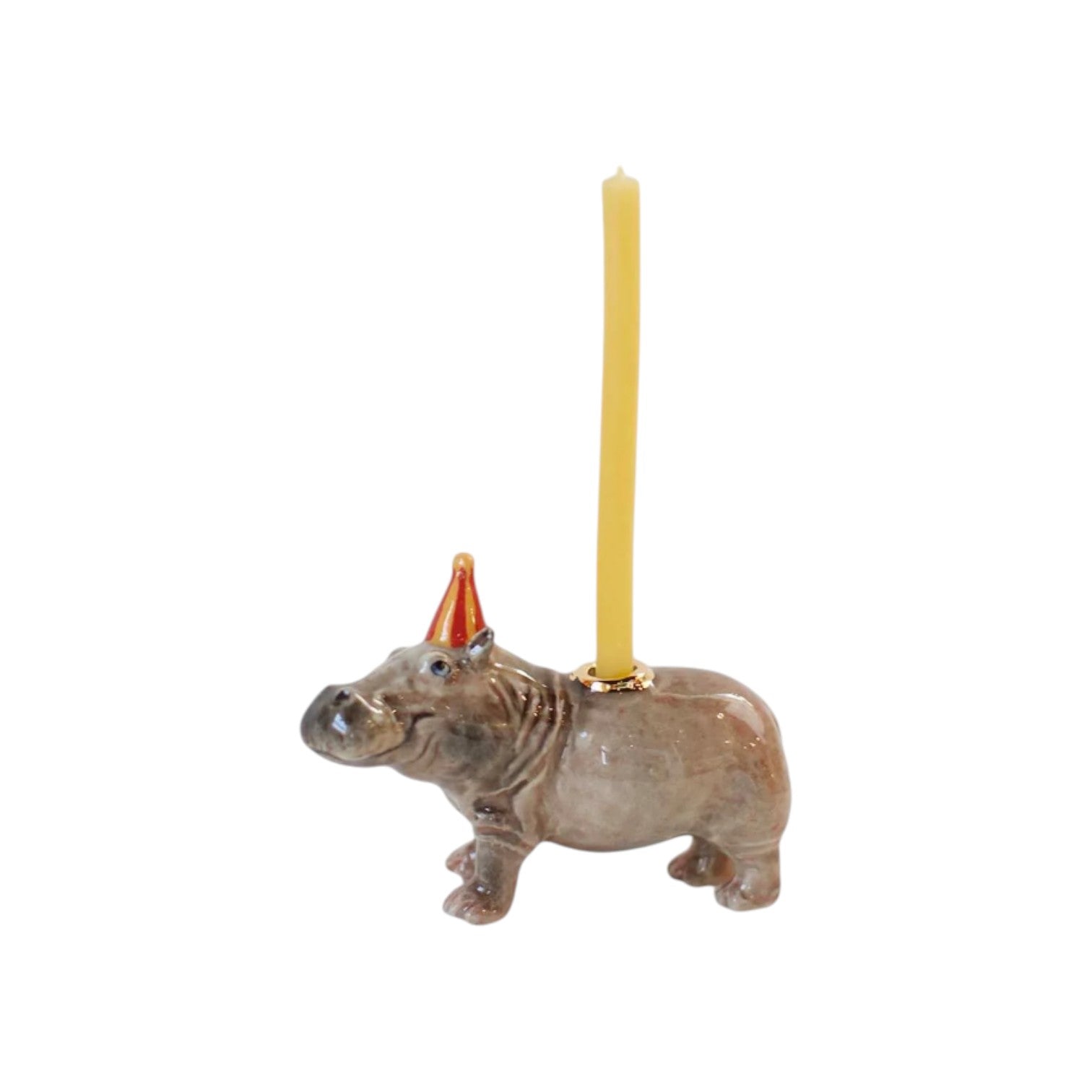 The Tiny Finch hand-painted porcelain hippo cake topper wearing a red party hat with a yellow birthday candle.