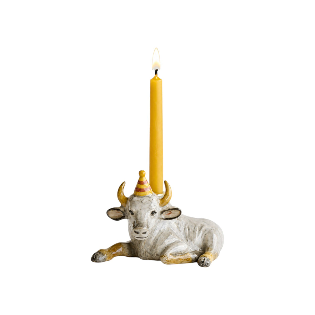 The Tiny Finch hand-painted porcelain ox cake topper wearing a party hat with a yellow candle on a white background