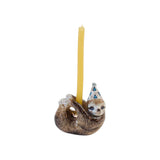 The Tiny Finch porcelain sloth cake topper wearing a party hat with a yellow candle, hand-painted in brown tones.