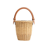 The Tiny Finch Jane Bag in natural handwoven rattan with a brown lizard-embossed leather top handle and closure.