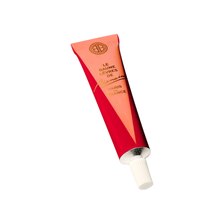 The Tiny Finch nourishing lip balm in a red squeeze tube with gold lettering and a white cap.