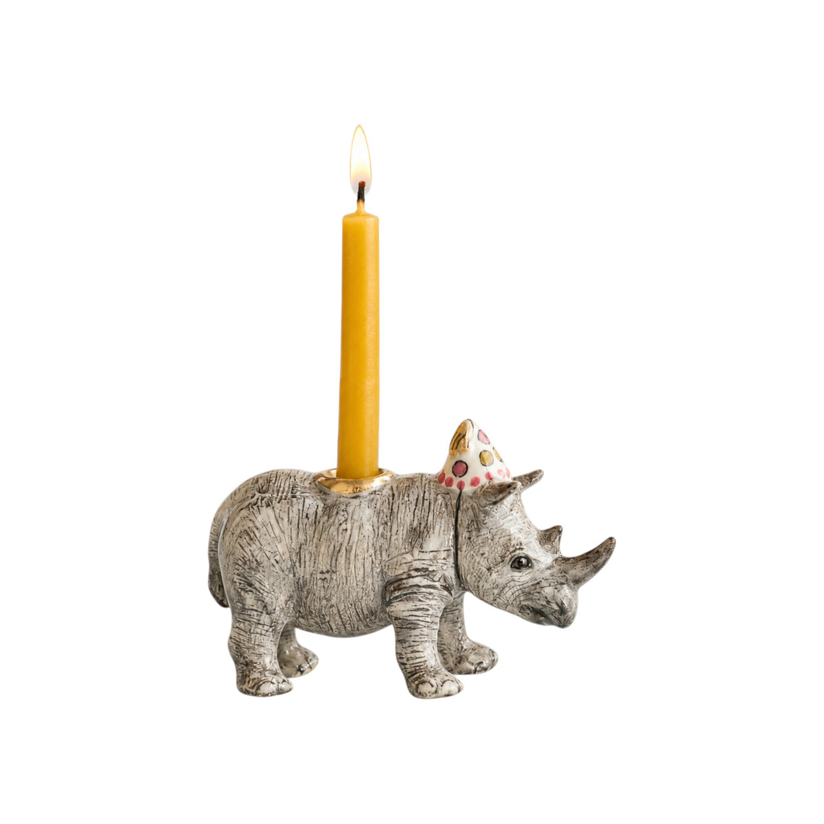 The Tiny Finch porcelain rhino cake topper wearing a polka dot party hat with a lit yellow birthday candle