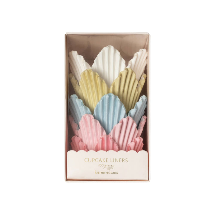 The Tiny Finch tulip-shaped cupcake liners in pastel pink, blue, yellow, and white, packaged in a clear gift box.