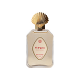 The Tiny Finch Bienaimé Vermeil eau de parfum in a clear glass bottle with a decorative gold shell-shaped cap.