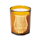 The Tiny Finch Trudon Altair candle in an amber glass vessel with a gold embossed crest label