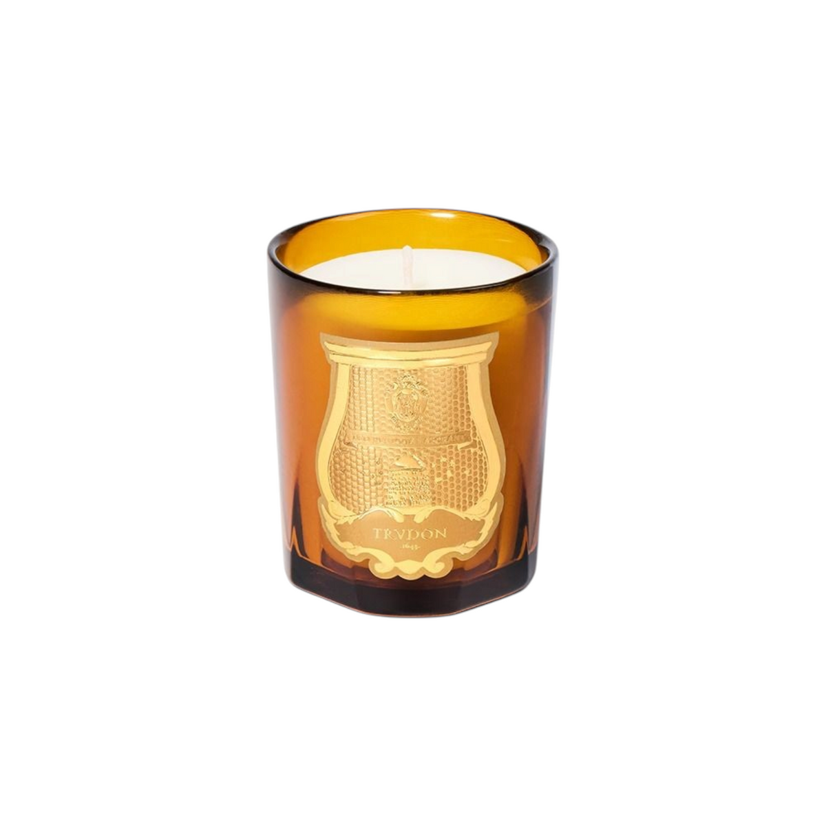 The Tiny Finch Trudon Altair candle in a warm amber glass jar with a gold embossed emblem on a white background.