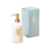 The Tiny Finch Trudon Vixi scented hand lotion in a white ribbed bottle with a gold pump next to its light blue box.