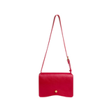 The Tiny Finch Val crossbody bag in carmine red leather with a brass hexagonal clasp and adjustable shoulder strap.